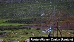 Un băiat poartă steagul național al Israelului în colonia Mitzpe Kramim, la est de orașul Ramallah din Cisiordania.. Fotografie de arhivă. 