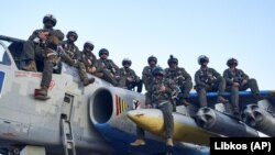 Пілоти Повітряних сил ЗСУ позують для фото, сидячи на штурмовику Су-25, на своїй базі на сході України, травень 2023 року
