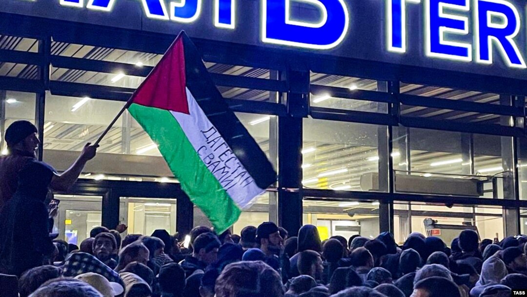 Un bărbat flutură un steag palestinian pe care scrie „Daghestan este alături de tine” în timpul unui miting pro-palestinian la aeroportul din Mahacikala, după sosirea unui zbor de linie de la Tel Aviv, pe 29 octombrie.