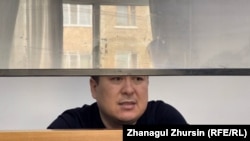 Ақтөбедегі Қаңтар оқиғасынан соң айып тағылып, қаңтар айында тергеу абақтысына қамалған Ернұр Әжниязов (суретте) сот залындағы әйнек қоршаудың ішінде отыр. Ақтөбе, 14 қазан 2022 жыл.