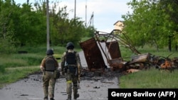 Українські військові йдуть біля знищеної військової машини в селі Руська Лозова, на Харківщині, Україна, 28 травня 2022 року. Фото ілюстративне