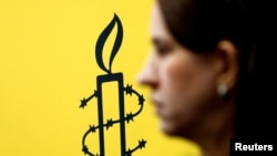 Логото на Амнести Интернешнл покрај директорот на Мујерес Ен Линеа Луиза Кислингер, за време на прес-конференција за објавување на резултатите од истрагата за кршење на човековите права извршени во Венецуела