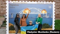 Твір мистецтва у формі великої марки, на якій зображено Кримський міст у вогні. Центр Києва, 8 жовтні 2022 року