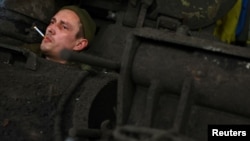 A member of a Ukrainian tank crew, call sign "Tyagach," waits for mechanics to maintain his tank after returning from a mission at the front line in Bakhmut on April 3.