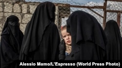 Россиянка ждет в очереди разрешения выйти за пределы лагеря Аль-Хол в Сирии для членов семей иностранных боевиков «Исламского государства». В лагере содержались приблизительно 10 тысяч человек 48 национальностей. Эта фотография сделана 14 ноября 2019 года.