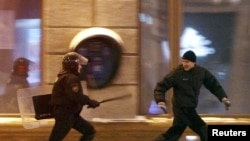 Polisiýa işgäri demonstranty kowalaýar, Minsk, 2010-njy ýylyň 19-njy dekabry.