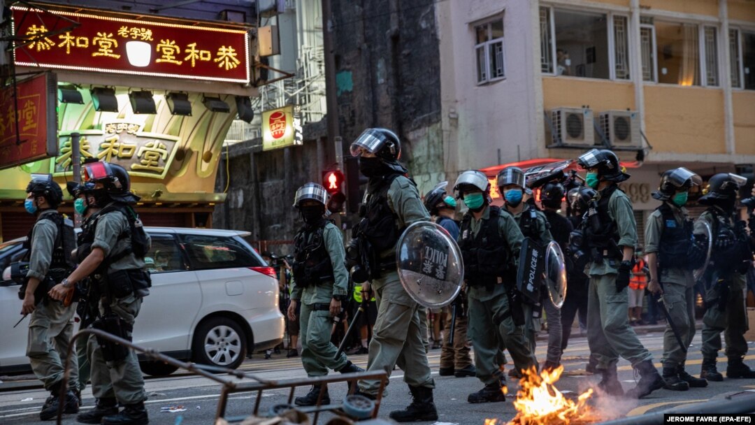 Policajci prolaze pored improvizirane barikade koju su zapalili demonstranti tokom skupa protiv zakona o nacionalnoj sigurnosti u Hong Kongu, Kina, 1. jula 2020.