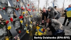 Oamenii depun flori la memorialul dedicat manifestanților care au murit în ciocnirile din 2014 cu forțele de securitate din Piața Independenței din Kiev