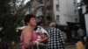 Жінка тримає свого собаку, разом з яким покинула пошкоджений російською атакою будинок